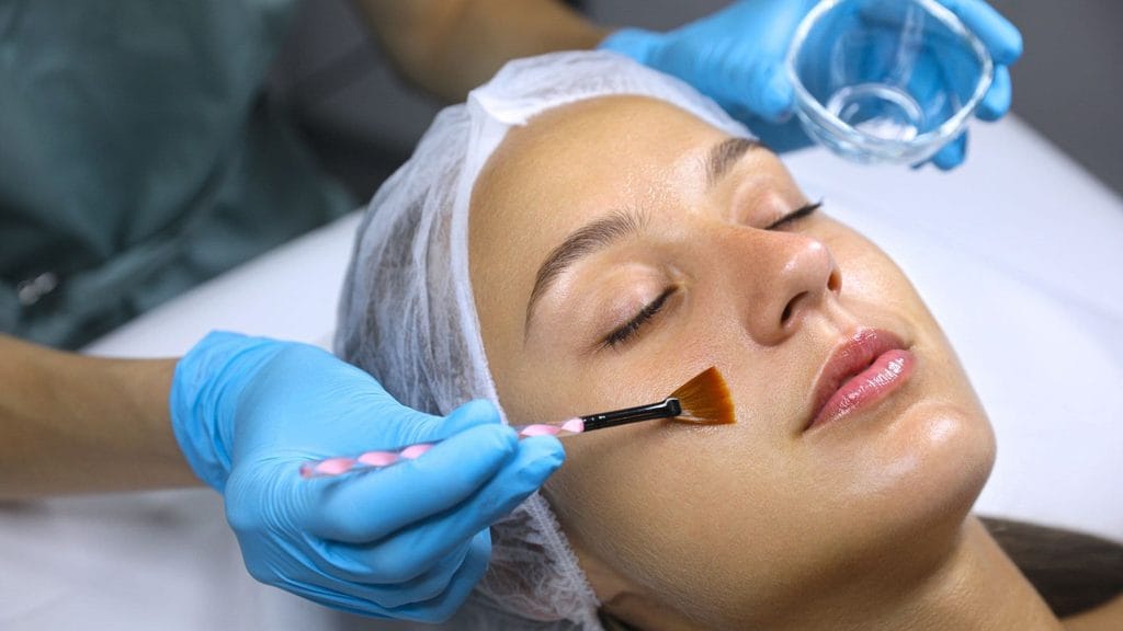 Esthetician applying a chemical peel solution to a patient's face