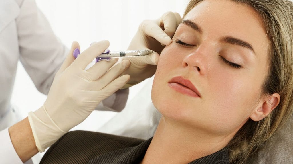 Provider injecting a dermal filler like Sculptra into a patient's cheek